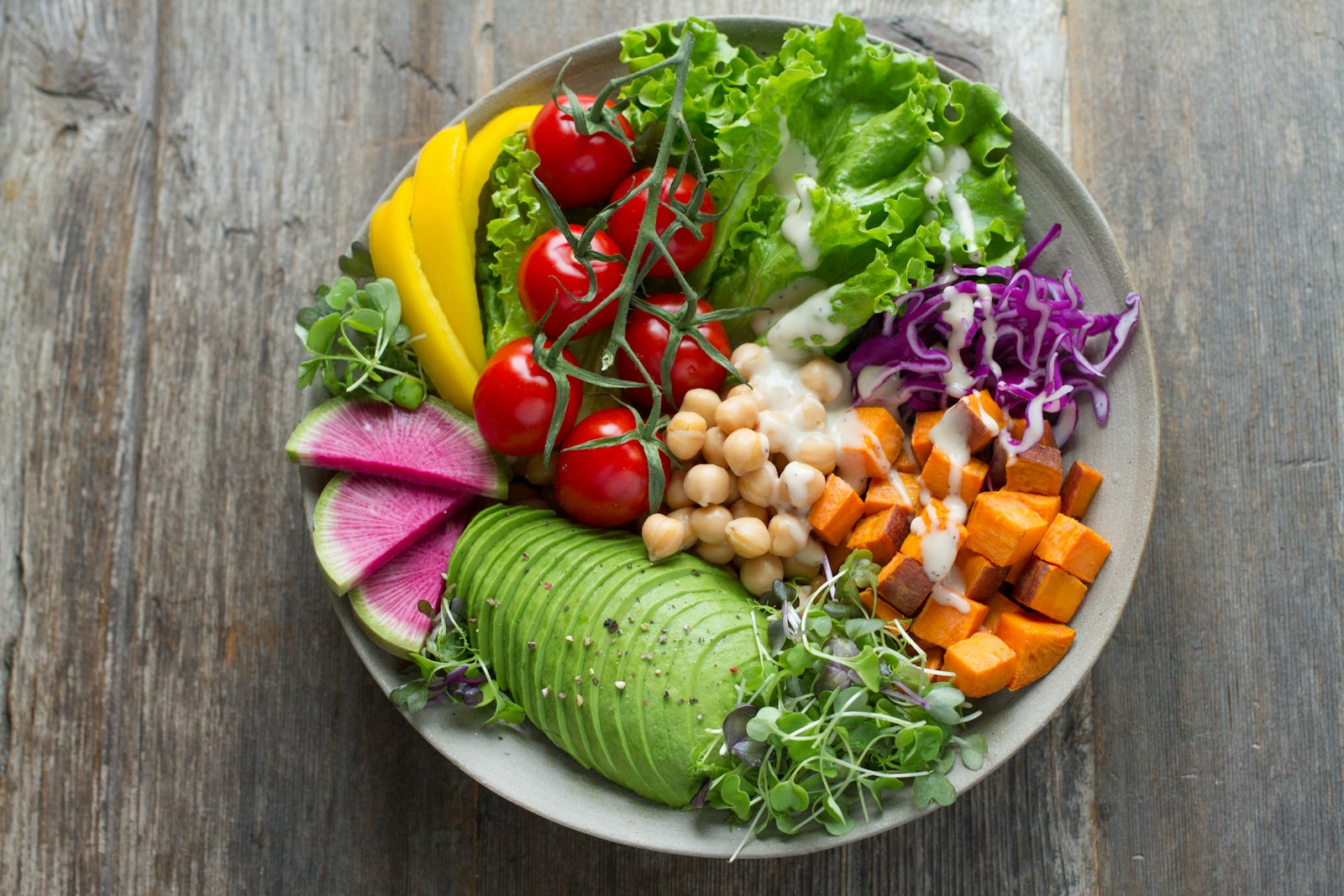 Colourful healthy bowl with fresh vegetables, avocado, chickpeas and greens